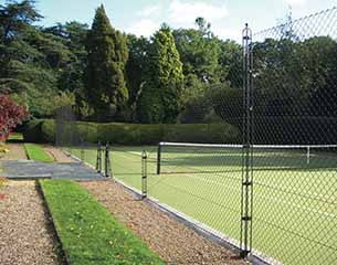 Tennis Court Construction - Mature trees and an obelisk fence surround an AMSS tennis court